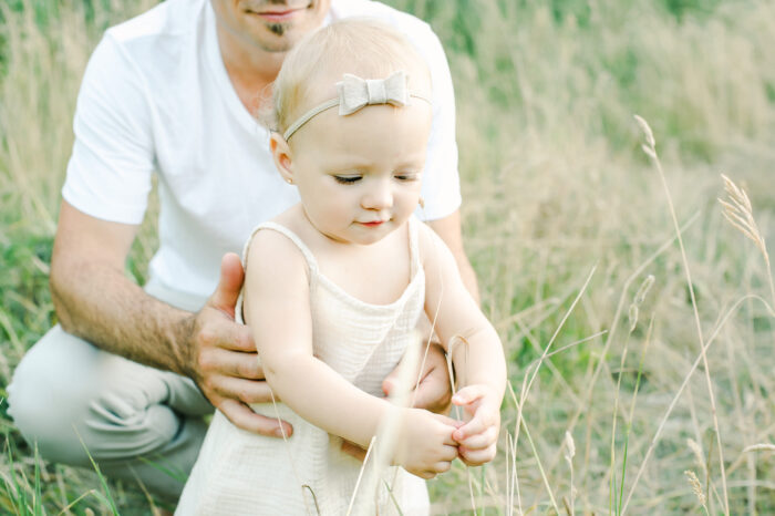 daddy's holds his daughter in field of green
