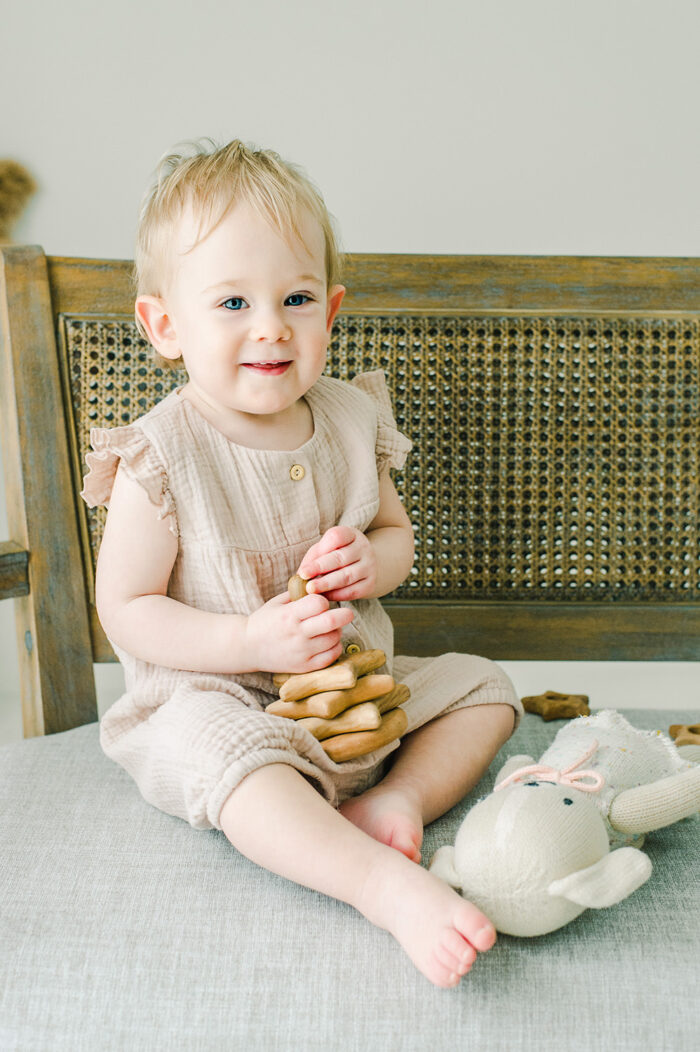 smiling baby girl playing with natural wood toys