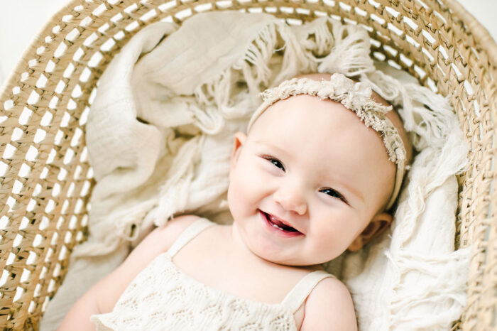 baby girl laughing in moses bassinet