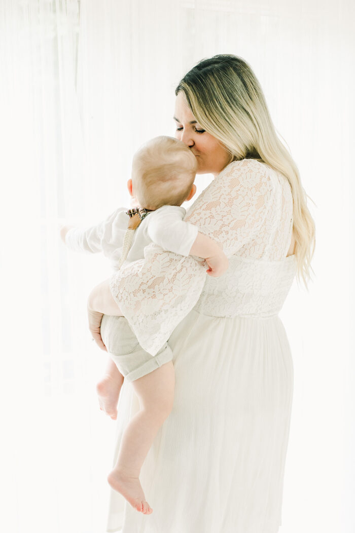 mother kisses her one year old sons head